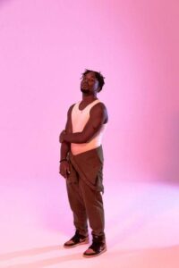 Le rappeur liégeois DIZY pose fixe dans un studio, entouré d'un couleur rose